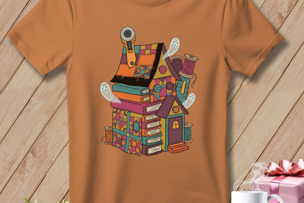 T-shirt with a quirky sewing-themed house illustration featuring books, ghosts, and sewing supplies.