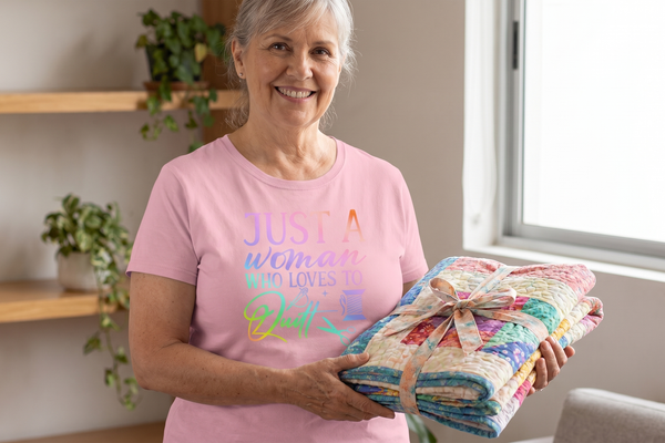A quilter holding her finished quilt tied with a ribbon, wearing the Just A Woman Who Loves To Quilt relaxed-fit tee