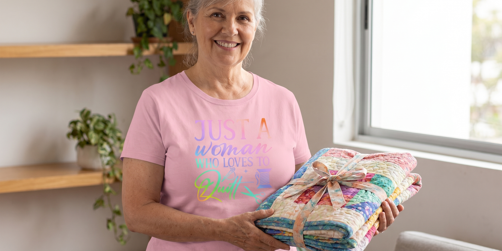 A quilter holding her finished quilt tied with a ribbon, wearing the Just A Woman Who Loves To Quilt relaxed-fit tee