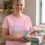 A quilter holding her finished quilt tied with a ribbon, wearing the Just A Woman Who Loves To Quilt relaxed-fit tee