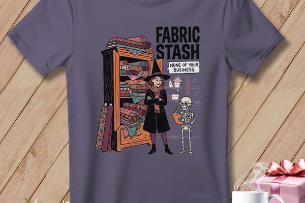 T-shirt graphic of a witch by a fabric stash with text: "FABRIC STASH NONE OF YOUR BUSINESS."