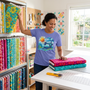 A quilter pulling bold print fabrics for a summer stack, wearing the Surfing the Fabric Sea premium tee