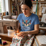 A quilter deep in concentration at her machine, wearing the Resting Stitch Face tee