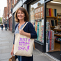 A quilter outside the fabric shop carrying the Just A Woman Who Loves To Quilt tote bag