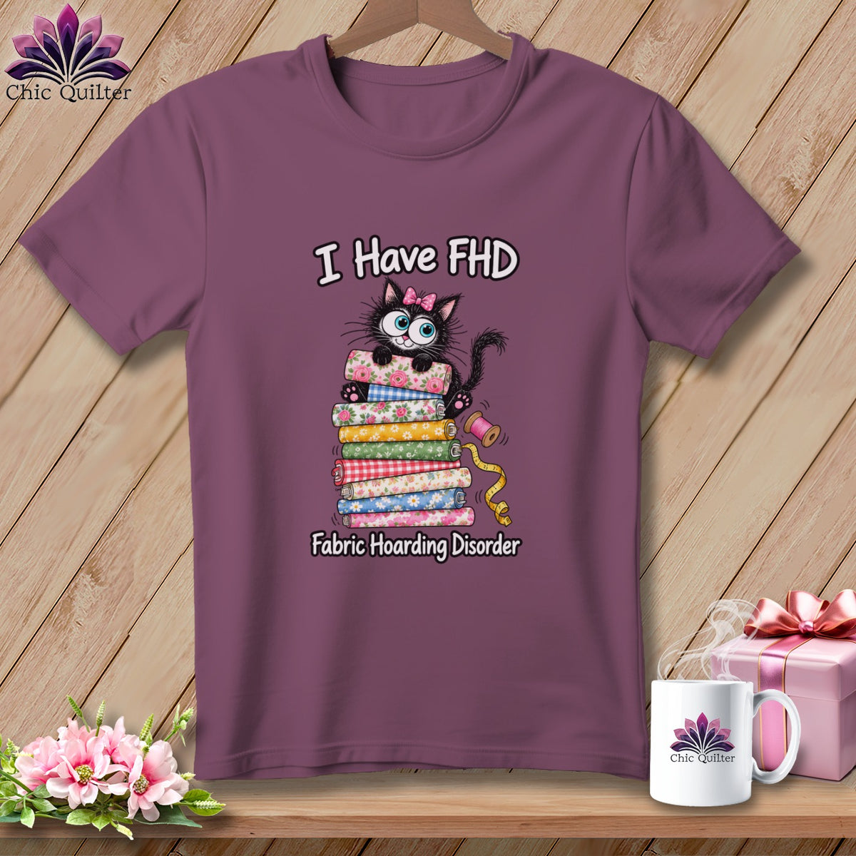 A mauve t-shirt features a graphic of a black cat on a fabric stack with the text I Have FHD Fabric Hoarding Disorder.