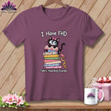 A mauve t-shirt features a graphic of a black cat on a fabric stack with the text I Have FHD Fabric Hoarding Disorder.