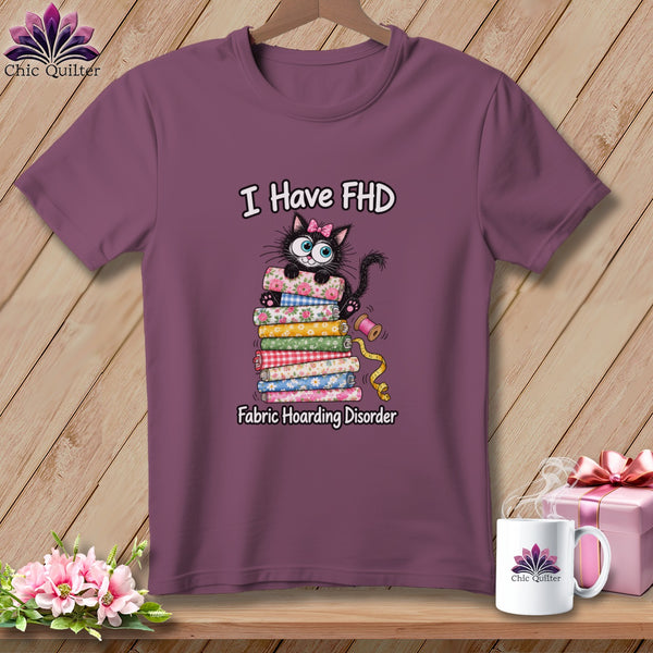 A mauve t-shirt features a graphic of a black cat on a fabric stack with the text I Have FHD Fabric Hoarding Disorder.