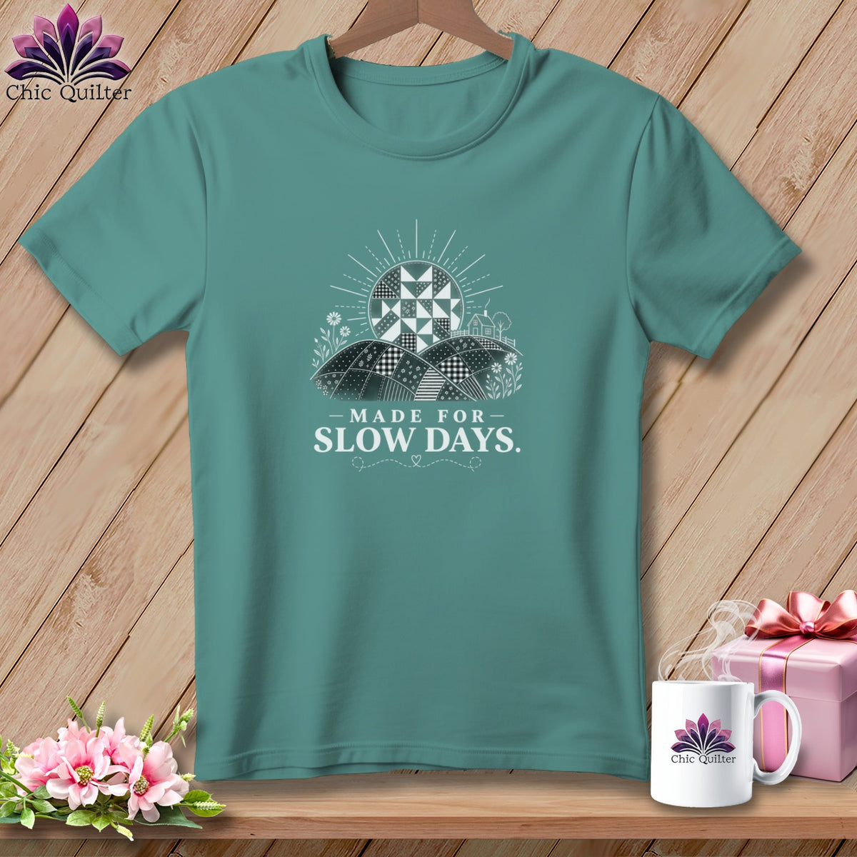 Teal t-shirt with a graphic of a quilted sun over rolling hills and the text "MADE FOR SLOW DAYS."