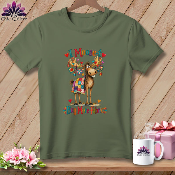 An olive green t-shirt featuring a cartoon moose graphic draped in a quilt with the text I Moose-t Buy More Fabric.