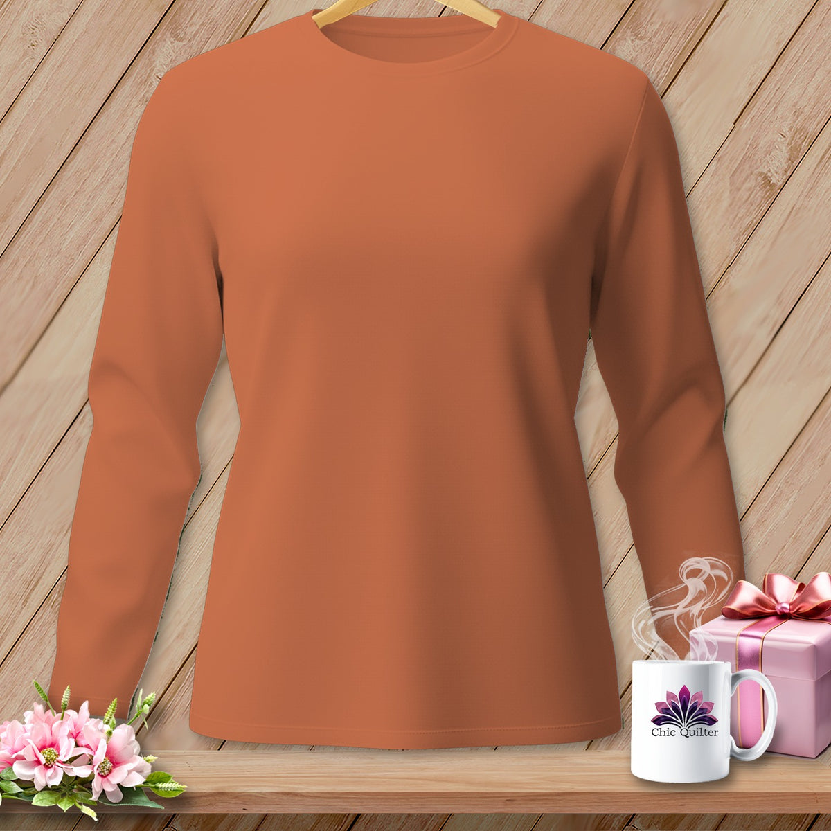 Orange long-sleeve shirt with flowers, gift, and mug on a wooden shelf.