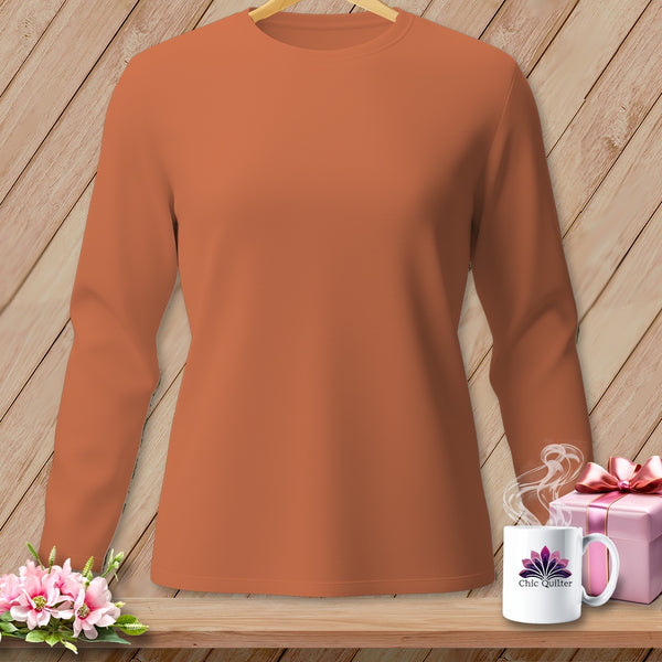 Orange long-sleeve shirt with flowers, gift, and mug on a wooden shelf.