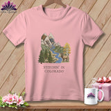 Pink t-shirt with a mountain, river, trees, and elk graphic, saying 