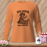 An orange long-sleeve shirt displays a graphic of an otter sewing a quilt wrapped around a sweating rabbit, with the text TUCK AROUND AND FIND OUT.