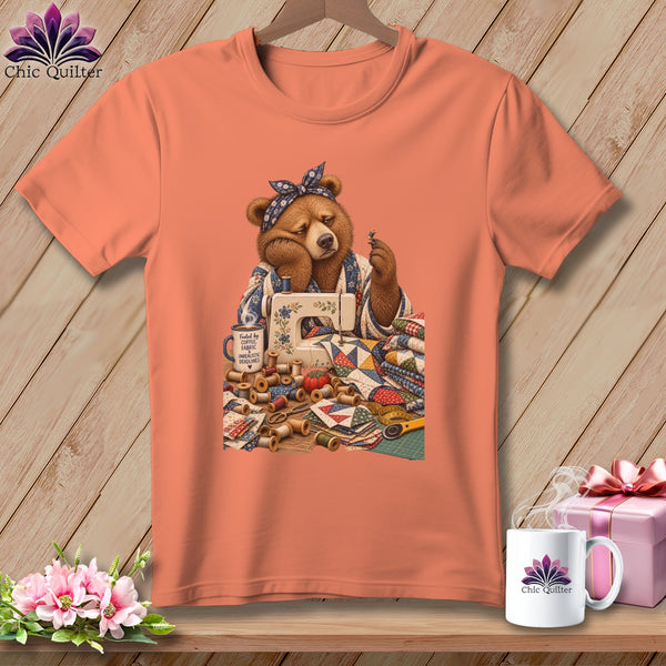Bear with sewing machine, fabric, and spools of thread, text "Fueled by coffee, fabric, unrealistic deadlines".