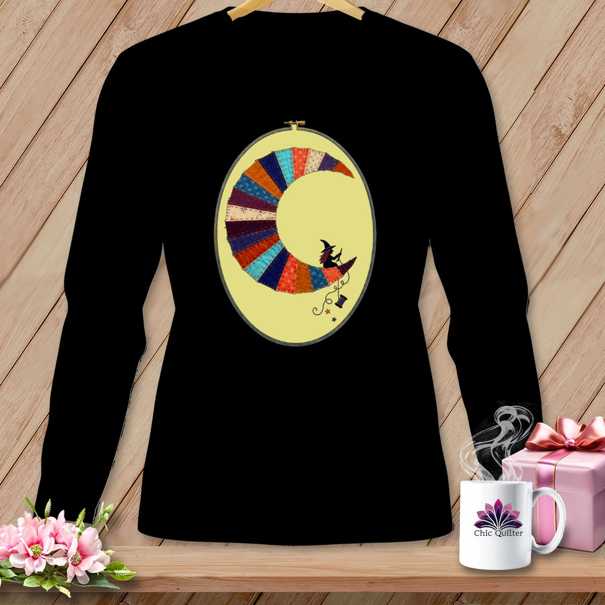 Black long-sleeve shirt with a crescent moon applique featuring a witch riding a broomstick.