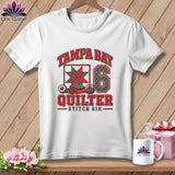White crewneck t-shirt featuring a Tampa Bay Quilter graphic with a red quilt block, the number six, and sewing tools.