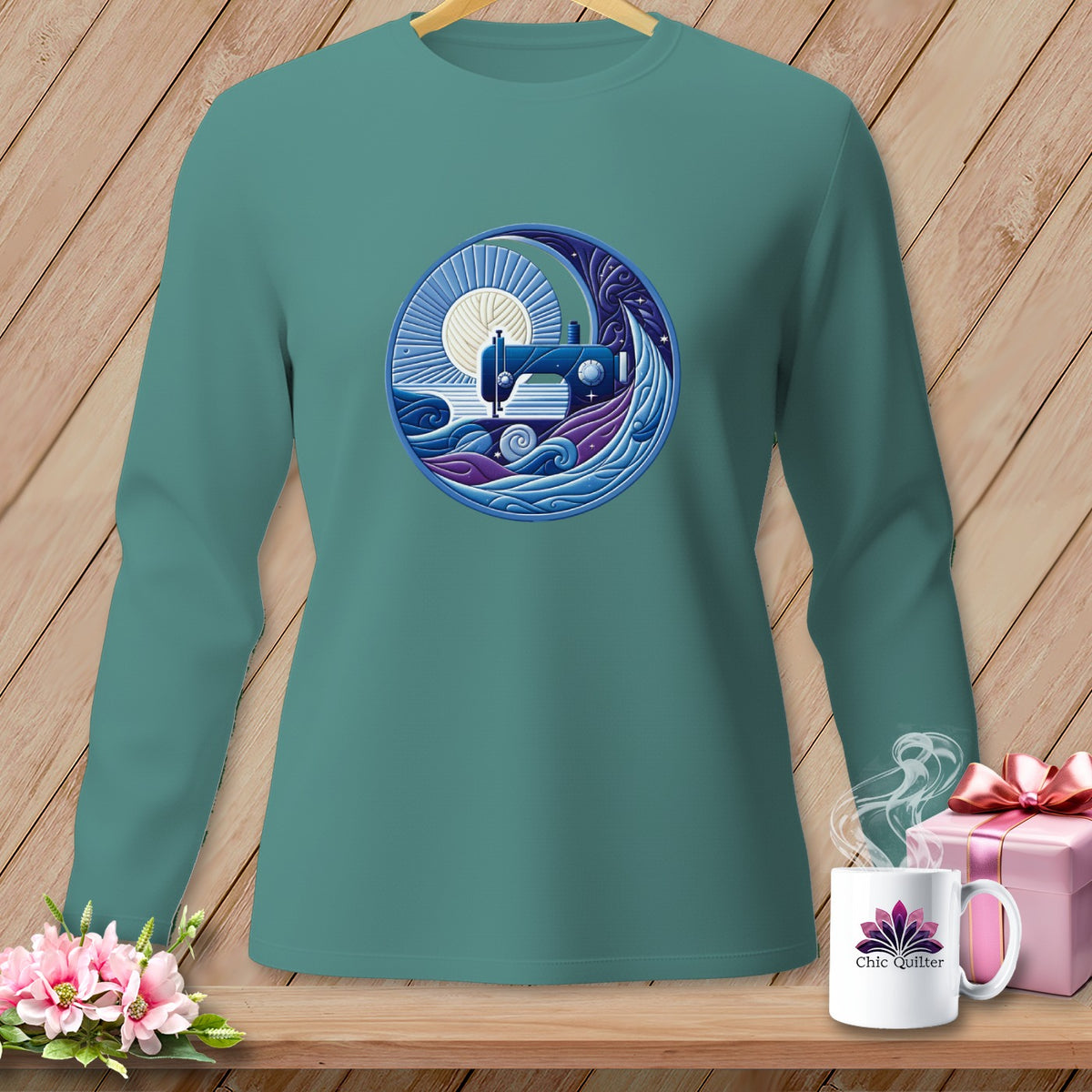 Teal long-sleeve shirt with a circular sewing machine and yarn graphic.