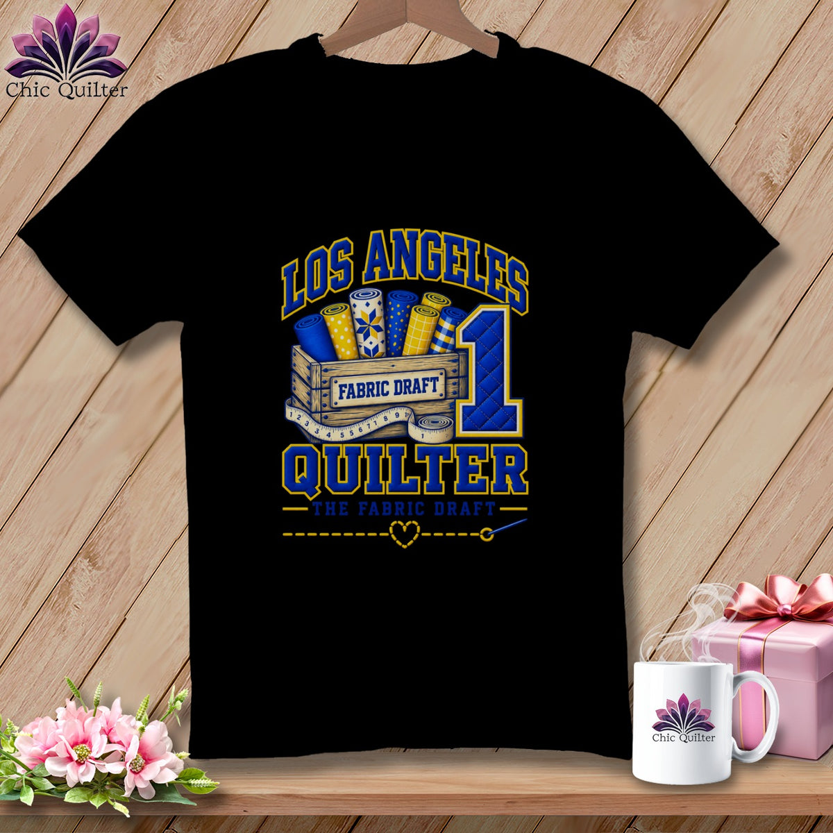 Black t-shirt featuring Los Angeles Quilter graphic with fabric rolls in a wooden crate and number one.