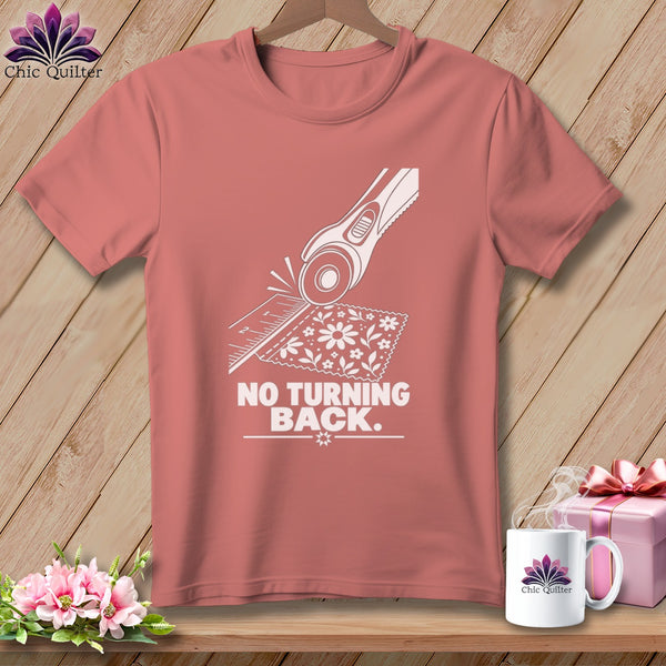 Peach t-shirt with rotary cutter, ruler, fabric graphic and text "NO TURNING BACK."