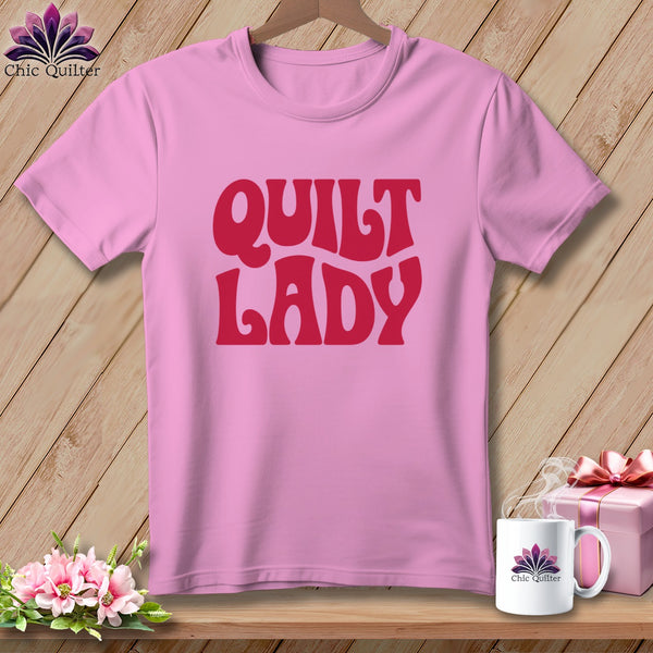 Pink t-shirt with red "Quilt Lady" text, coffee mug, and gift box.