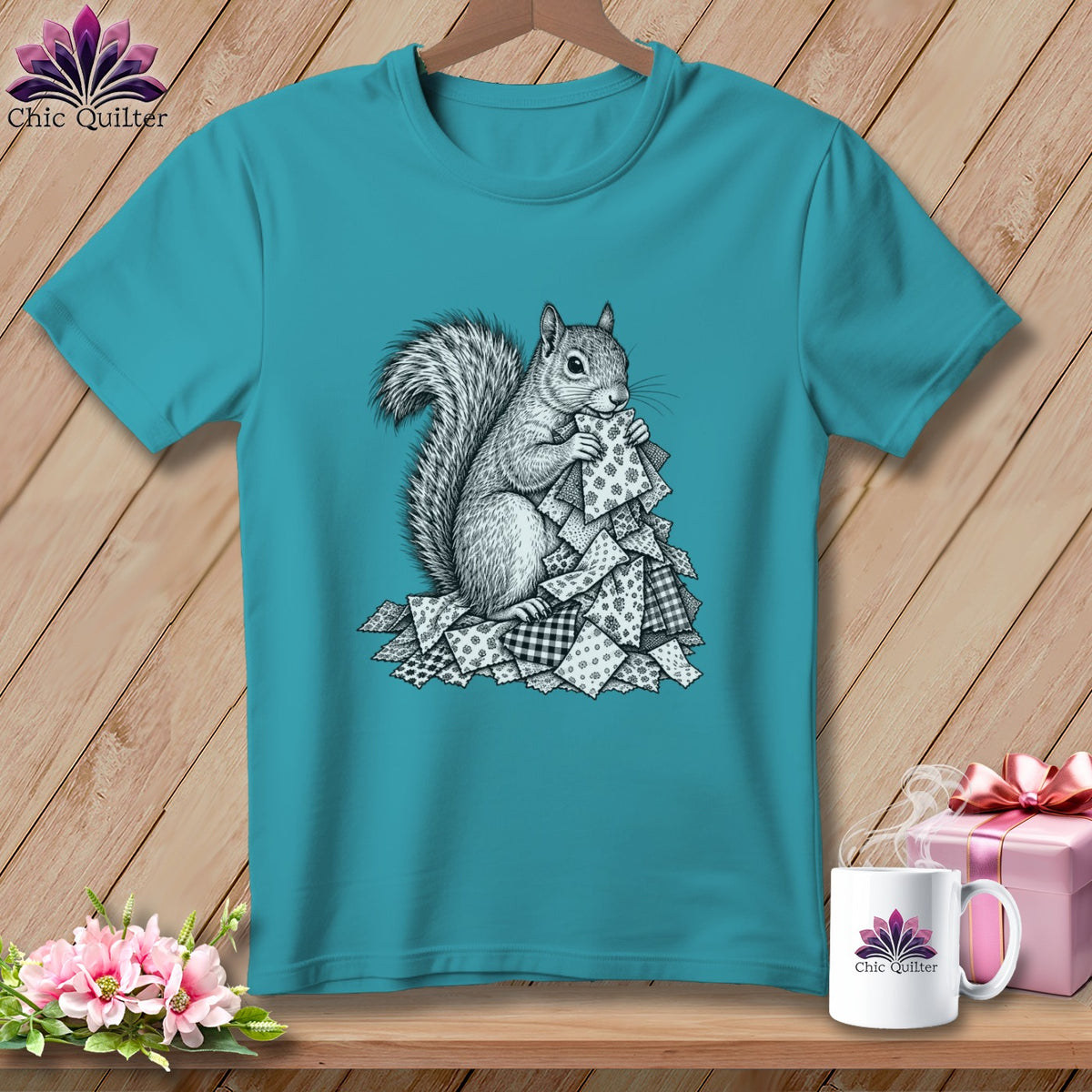 Turquoise crewneck t-shirt featuring a black-and-white graphic of a squirrel holding patterned fabric scraps.