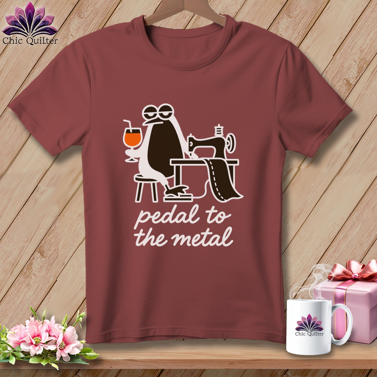 Maroon t-shirt with a penguin sewing and the text "pedal to the metal".