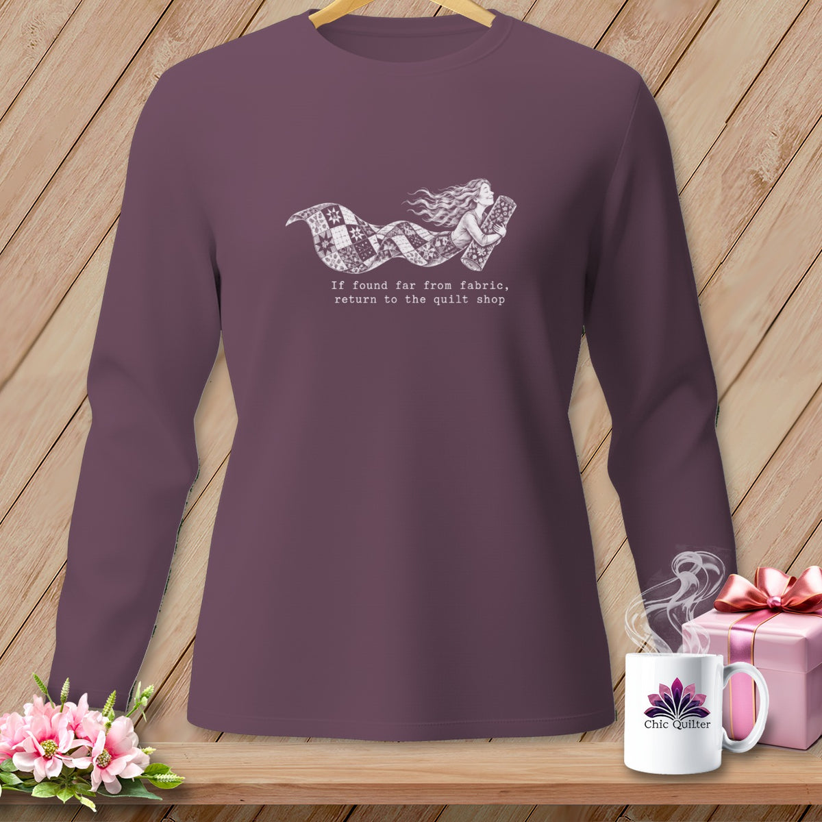 Long sleeve shirt with a graphic of a woman holding fabric and the text "If found far from fabric, return to the quilt shop."