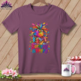 A purple t-shirt displays a colorful owl in a basket with the text Scrappy & Happy.