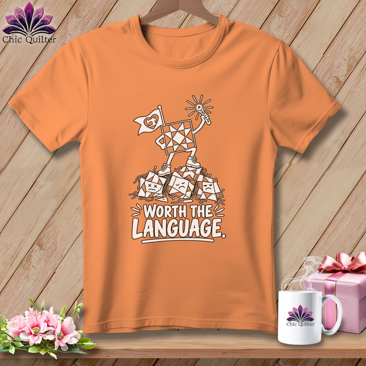 Orange t-shirt with a graphic of a quilt block character holding a flag and a sun, standing on sad quilt blocks.