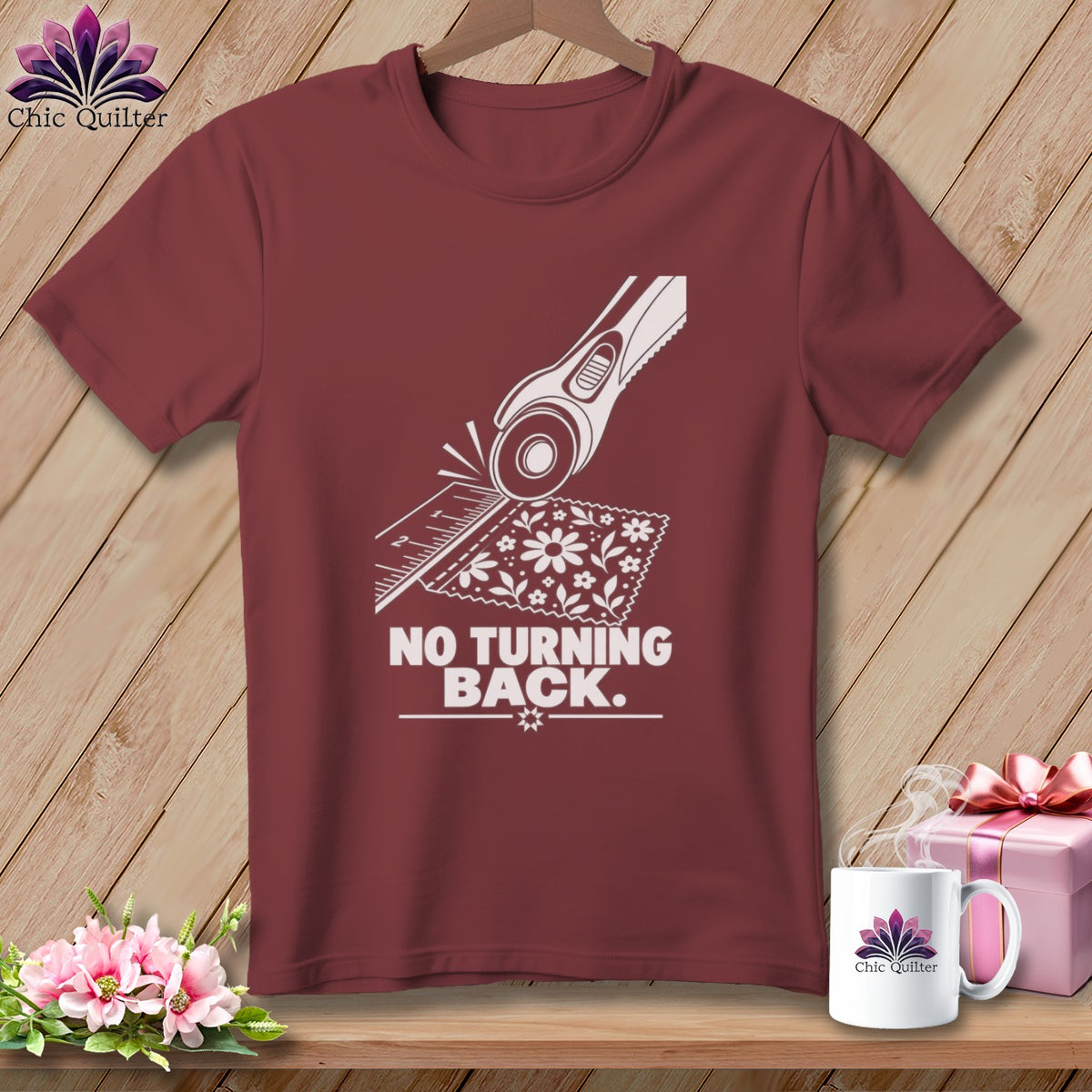Maroon t-shirt graphic featuring a rotary cutter, ruler, fabric, and the text "NO TURNING BACK."