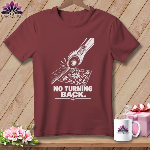 Maroon t-shirt graphic featuring a rotary cutter, ruler, fabric, and the text "NO TURNING BACK."