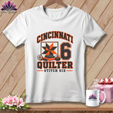 A white t-shirt features a Cincinnati Quilter graphic with a quilt square, number six, and sewing tools.