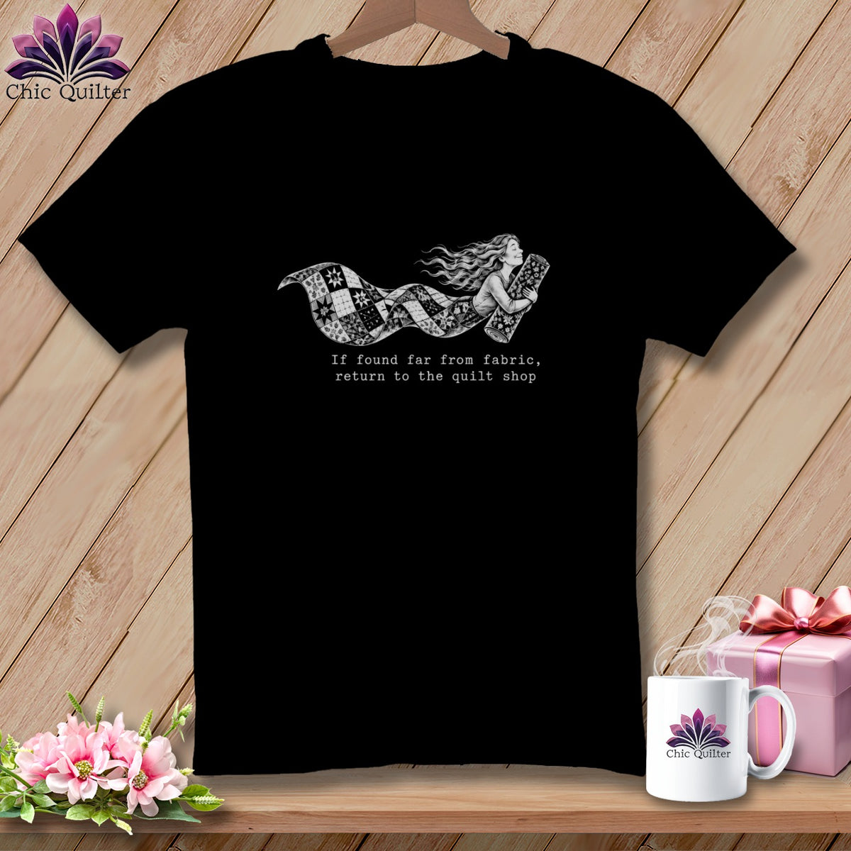Black t-shirt with a woman wrapped in a quilt, with text "If found far from fabric, return to the quilt shop".