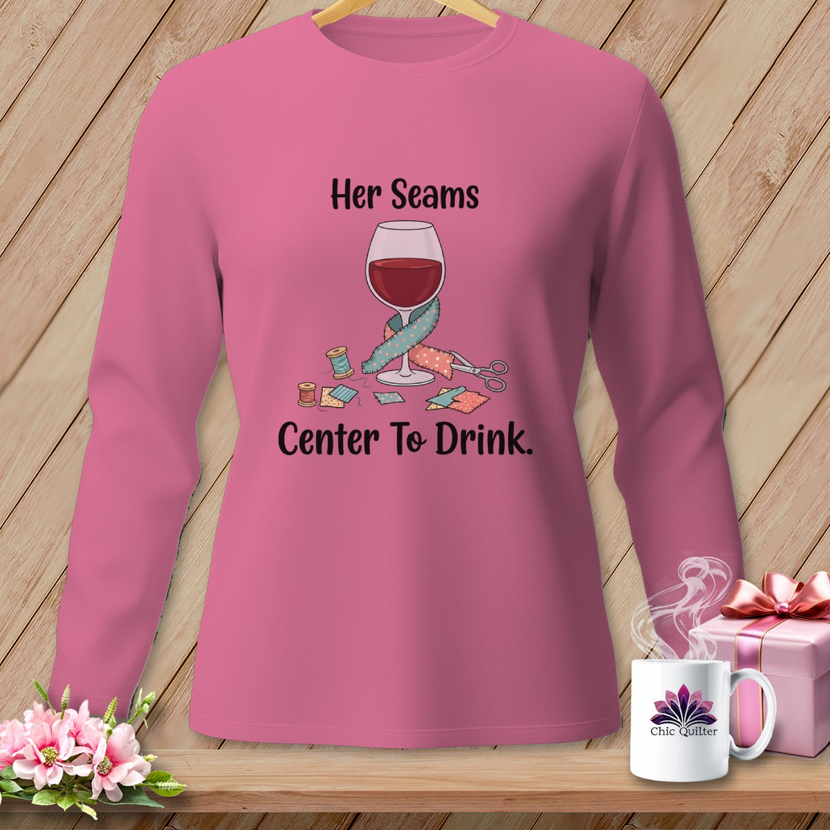 Pink long-sleeve shirt with "Her Seams Center To Drink" text and sewing graphics.