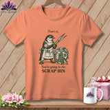 T-shirt with a drawing of a penguin holding scissors over a basket of fabric scraps.