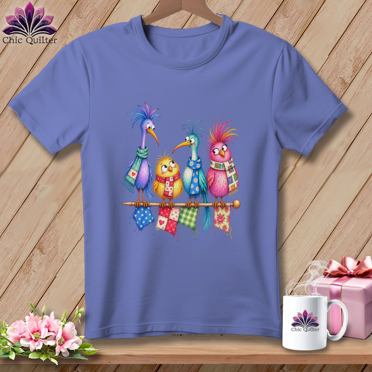 Purple crewneck t-shirt featuring an illustration of four colorful cartoon birds wearing scarves on a wooden background.