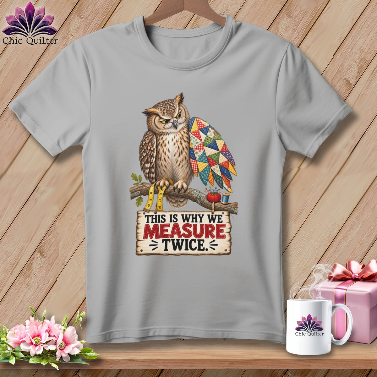 Gray t-shirt with an owl wearing glasses and a patchwork wing, holding a measuring tape.