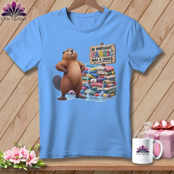 Light blue t-shirt with a beaver and stack of fabric, text reads "In hindsight, fabric was a choice."