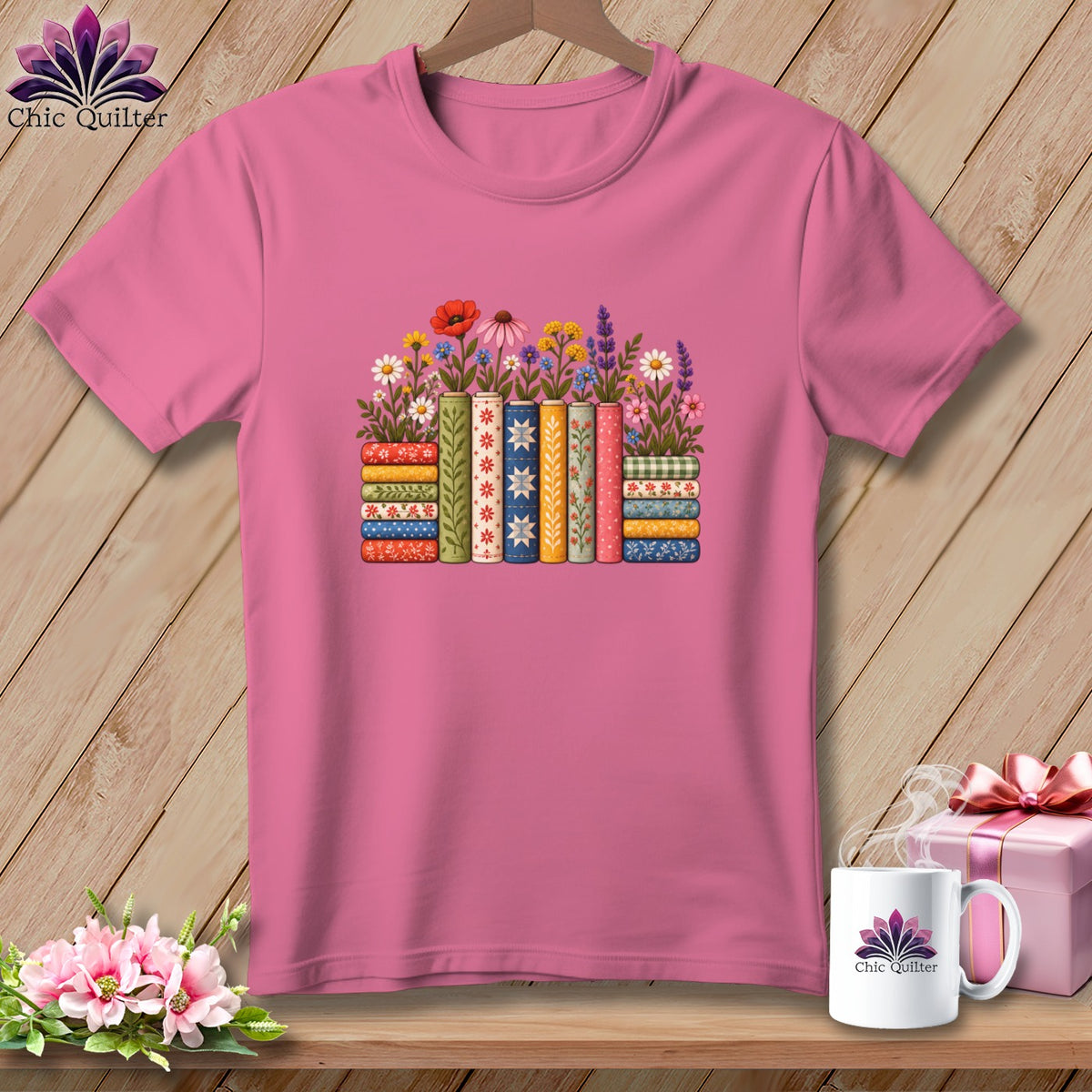 Pink crewneck t-shirt featuring a colorful graphic of stacked books adorned with flowers.