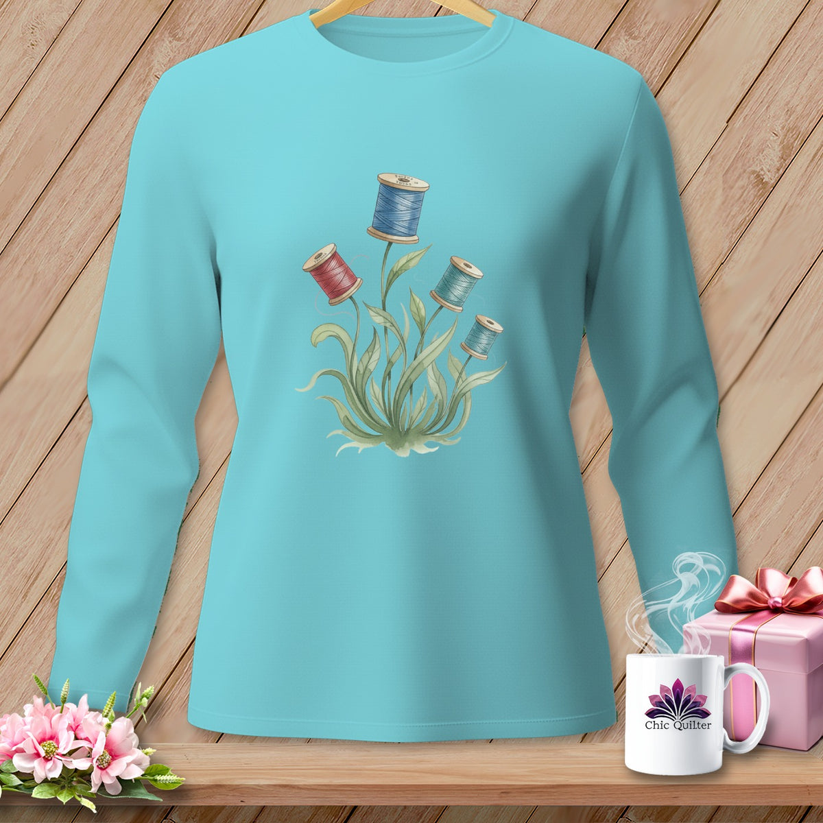 Turquoise long sleeve shirt with floral spools of thread graphic.