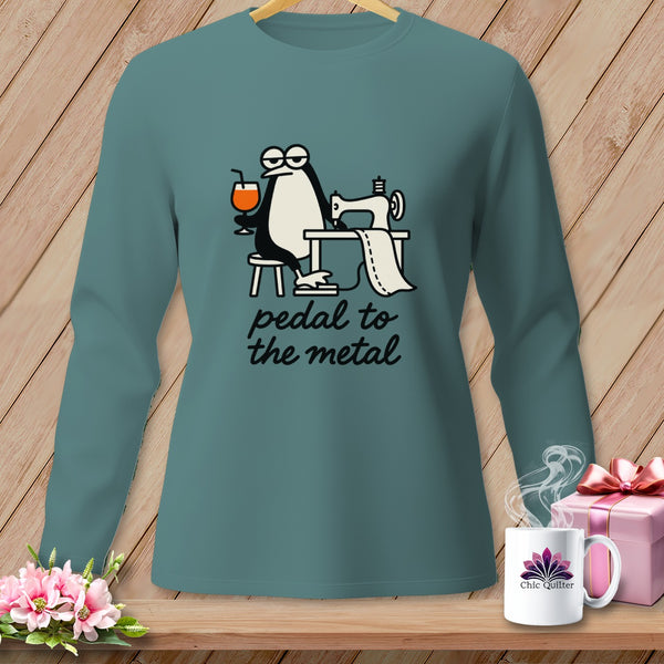 Long sleeve teal shirt with cartoon penguin sewing and text "pedal to the metal".