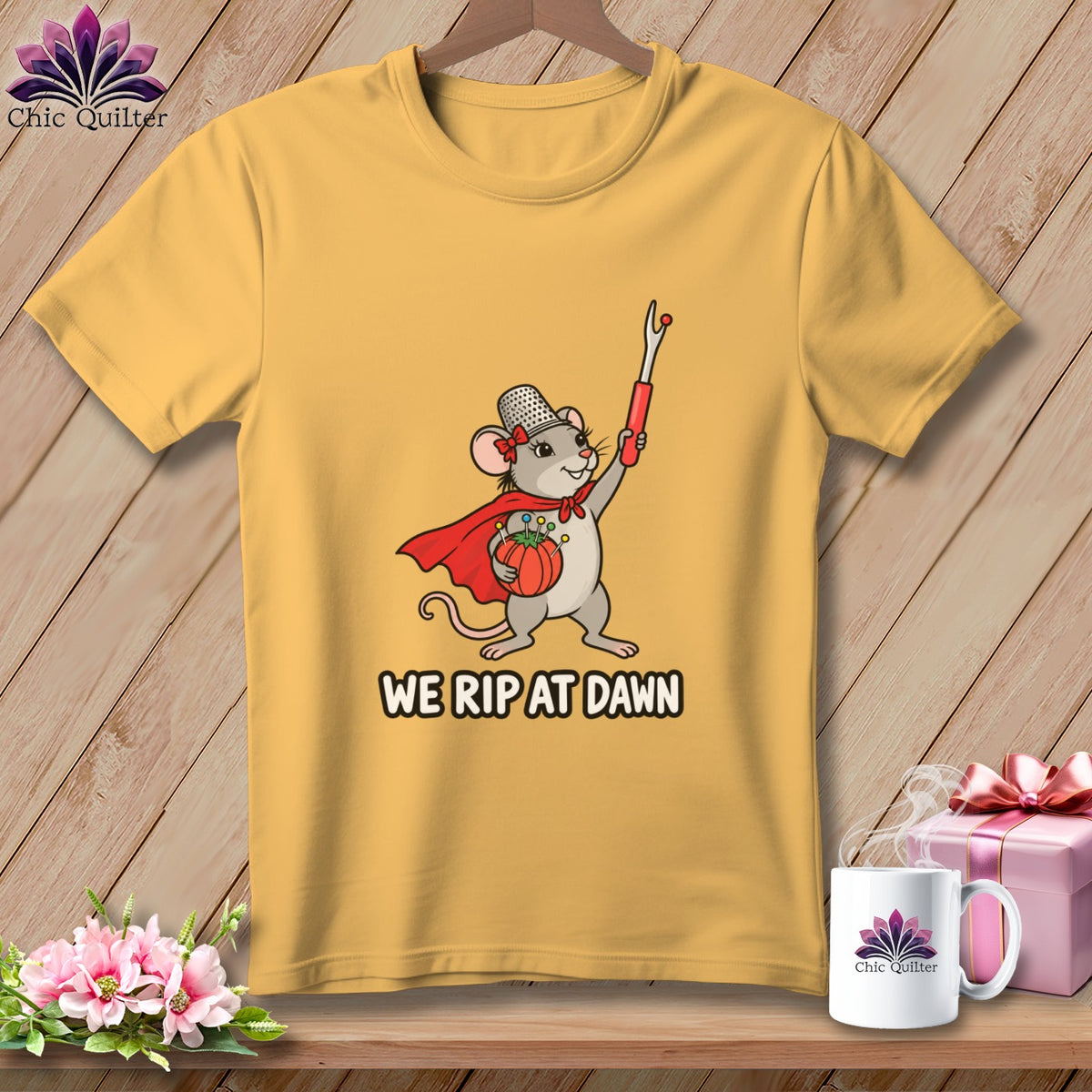 Yellow t-shirt featuring a cartoon mouse wearing a cape and thimble, holding a seam ripper and pincushion, with the text WE RIP AT DAWN.