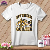 White t-shirt on a wooden hanger with New Orleans Quilter #14 graphic, next to a mug and pink gift box.