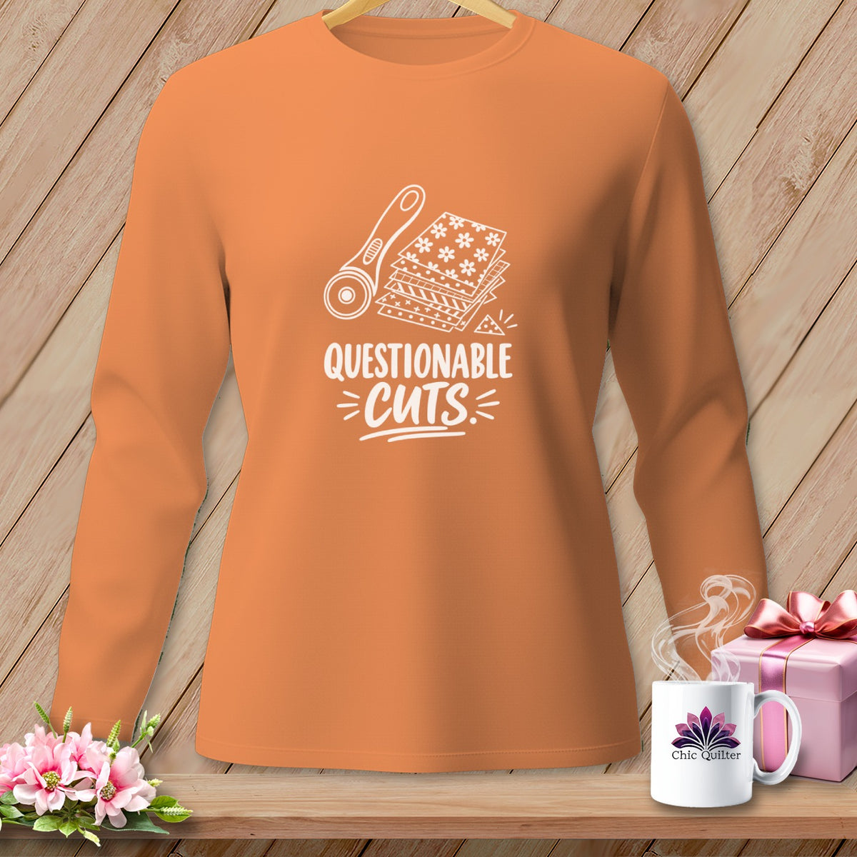 Orange long-sleeve shirt with a rotary cutter and fabric graphic and "Questionable Cuts" text.
