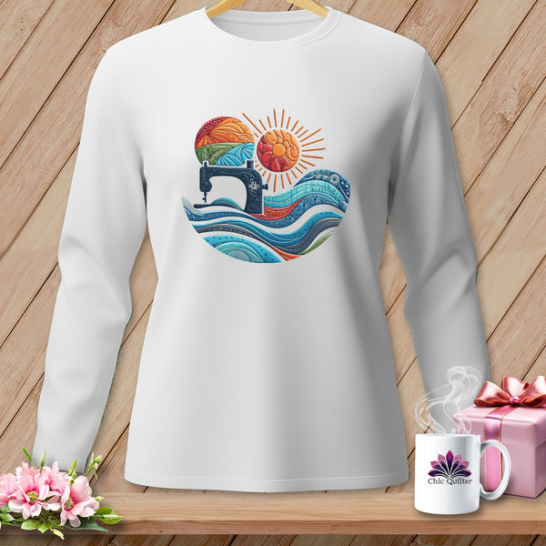 White long-sleeve shirt with a sewing machine, yarn, sun, and waves graphic.