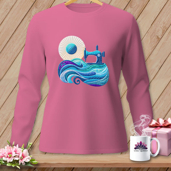 Pink long-sleeved shirt with a blue sewing machine on a wave of fabric.