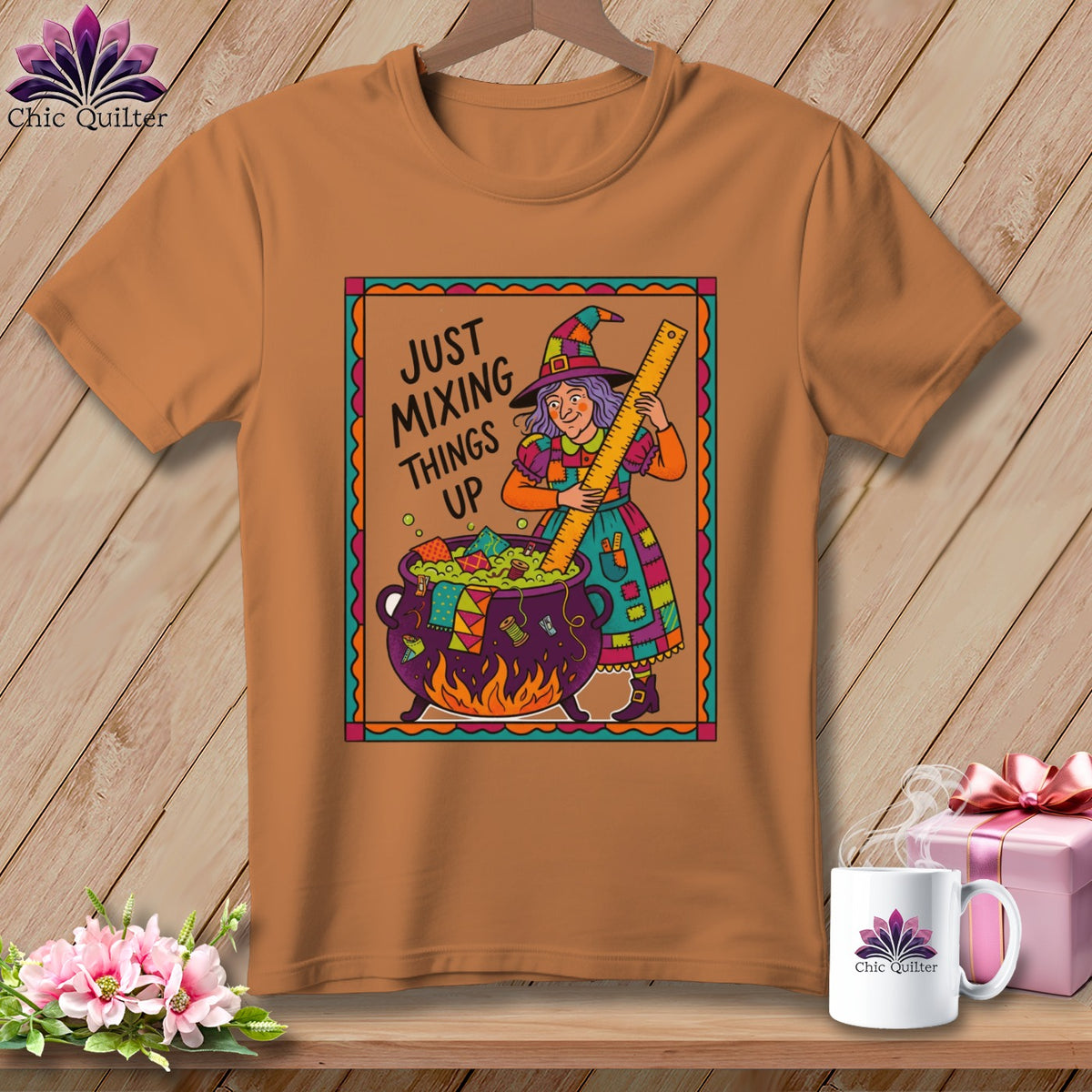 Brown t-shirt with a witch mixing fabric scraps in a cauldron and the text "Just Mixing Things Up".