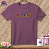 Plum crew neck t-shirt featuring a cartoon illustration of five racing thimbles on the chest.