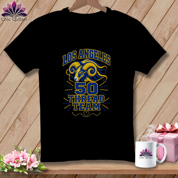 A black t-shirt hangs on a wooden background, featuring a blue and yellow Los Angeles 50 Thread Team ram graphic.