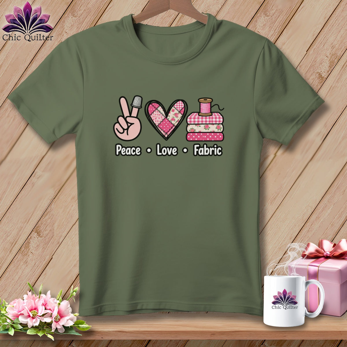 Olive green t-shirt with a Peace, Love, Fabric graphic featuring a thimble, heart, and folded fabrics.